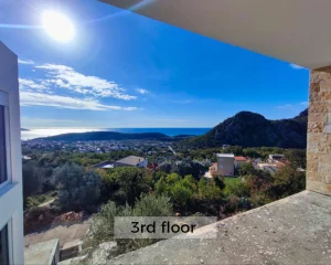 Trees and olive trees around the building in a tranquil location with a view of the sea in Sutomore, Montenegro.