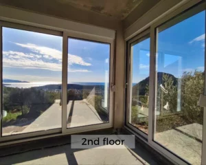 Panoramic windows overlooking the sea in the living room of the 2nd-floor luxury apartment for sale.